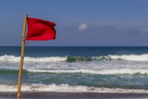 image of red flag on the beach. Learn how to handle toxic relationships with online relationship counseling with Foram Zaveri